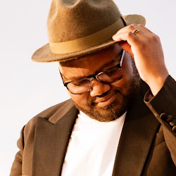 Portrait of a music producer wearing a fedora hat and glasses