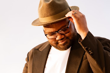 Portrait of a music producer wearing a fedora hat and glasses